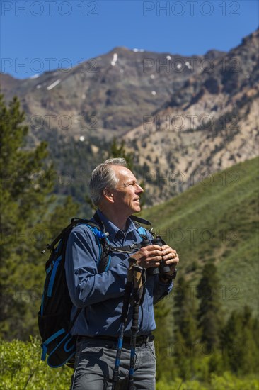 Caucasian man hiking in mountains with binoculars