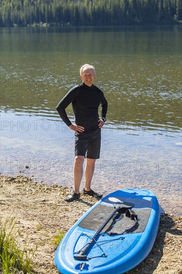 Smiling Caucasian man posing near paddleboard