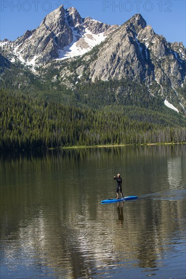 Caucasian man on paddleboard on mountain lake