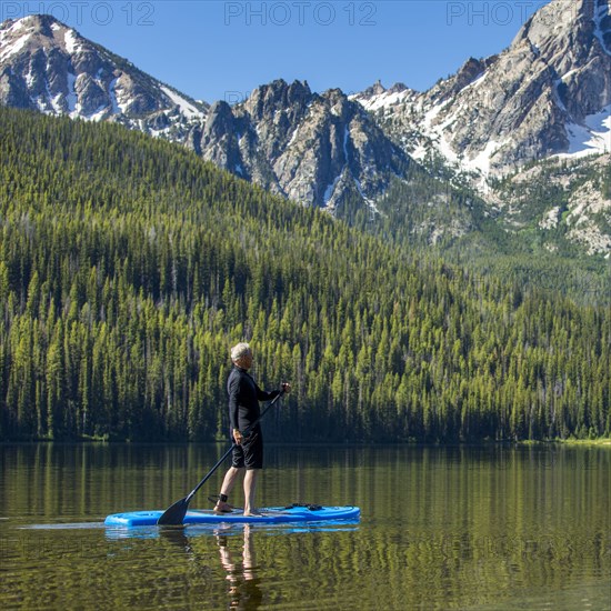 Caucasian man on paddleboard on mountain lake