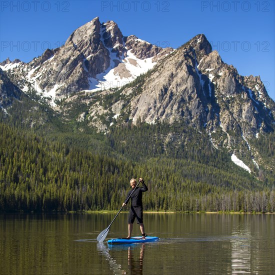 Caucasian man on paddleboard on mountain lake