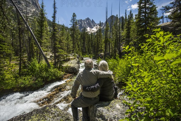 Caucasian couple hugging on rock at mountain river