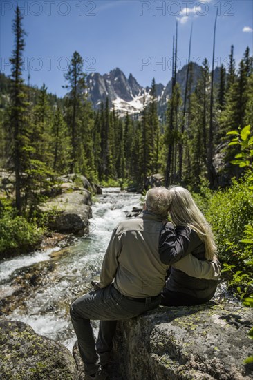Caucasian couple hugging on rock at mountain river