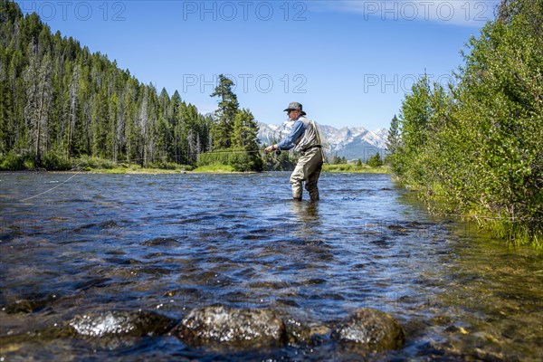 Caucasian man fly fishing in river