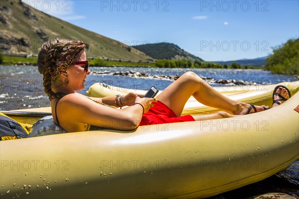 Caucasian woman laying in inflatable raft texting on cell phone