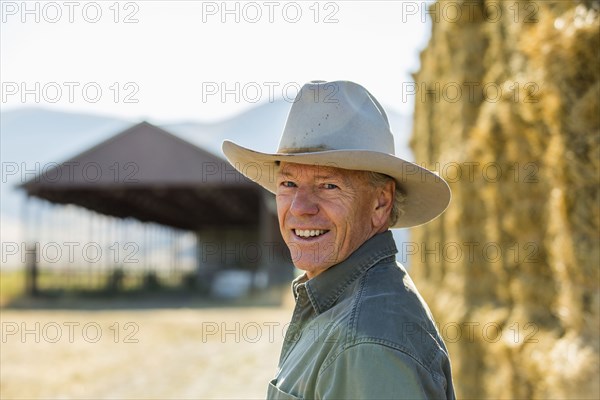 Smiling Caucasian farmer near stacks of hay
