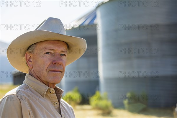 Serious Caucasian farmer near storage silos