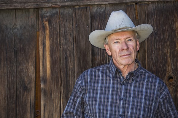 Serious Caucasian farmer near wooden fence