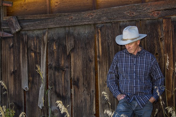 Pensive Caucasian farmer leaning on wooden fence