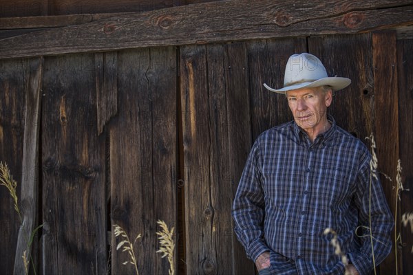 Serious Caucasian farmer leaning on wooden fence