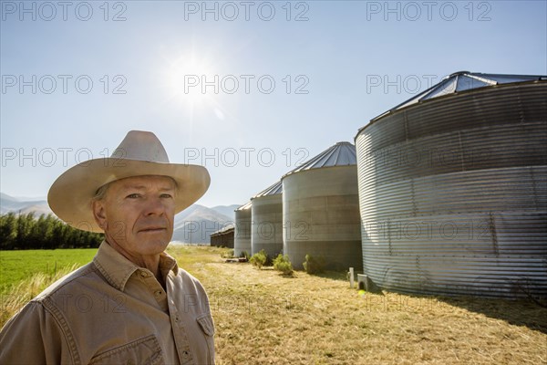 Serious Caucasian farmer near storage silos