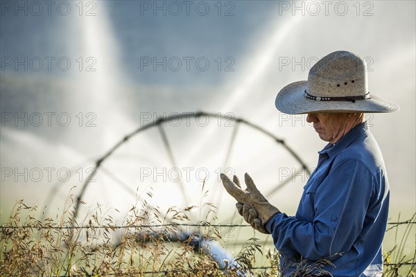 Caucasian farmer near barbed wire fence checking glove