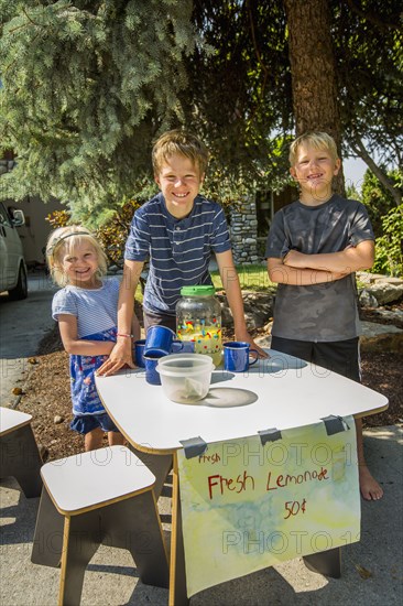 Smiling Caucasian boys and girl selling lemonade