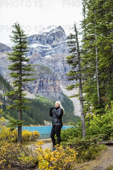 Caucasian woman using binoculars at mountain lake