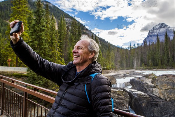 Caucasian man posing for cell phone selfie near mountain