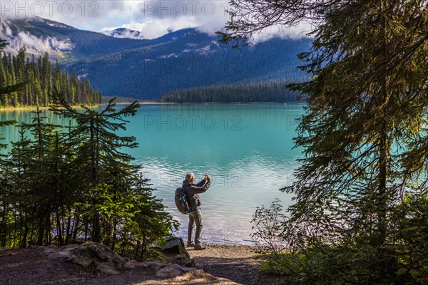 Caucasian man photographing mountain lake