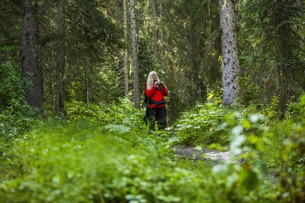 Caucasian woman using binoculars in forest