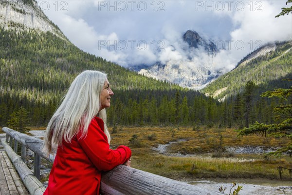 Caucasian woman leaning on wooden railing admiring mountain