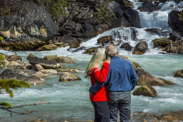 Caucasian couple admiring rapids over rocks