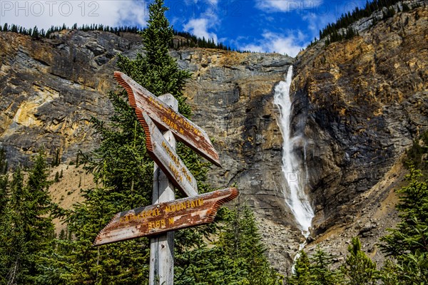 Sign near waterfall flowing over cliff