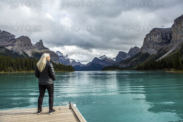 Caucasian woman standing at the end of dock on mountain lake