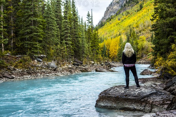 Caucasian woman standing on rock near mountain river