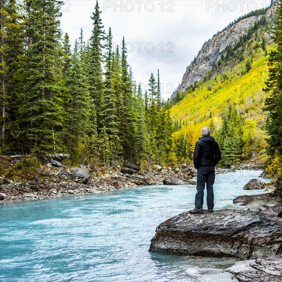 Caucasian man standing on rock near mountain river