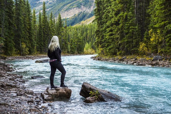 Caucasian woman standing on rock near mountain river