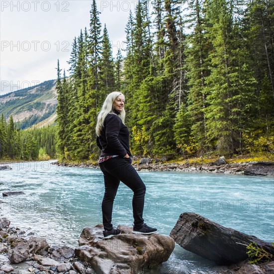 Caucasian woman standing on rock near mountain river