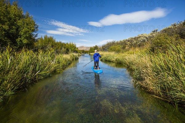 Caucasian woman paddleboarding on river