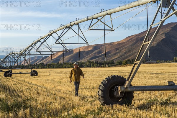 Caucasian farmer walking near irrigation equipment