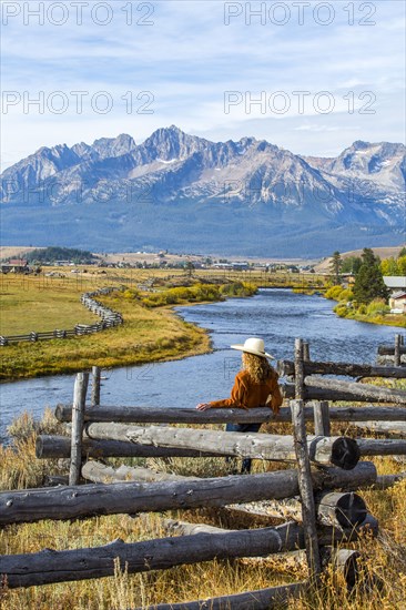Caucasian woman leaning on wooden fence at mountain river