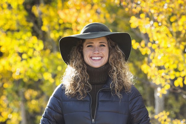 Smiling Caucasian woman under autumn leaves