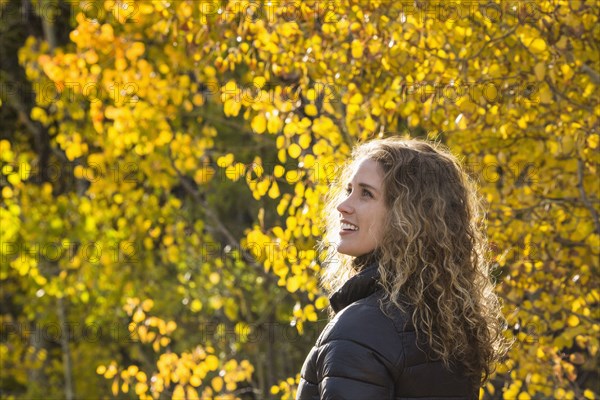 Smiling Caucasian woman under autumn leaves