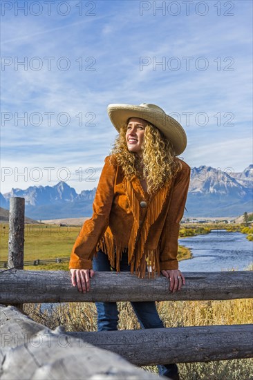 Caucasian woman leaning on wooden fence near mountain river