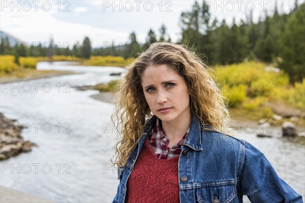 Serious Caucasian woman standing near winding river