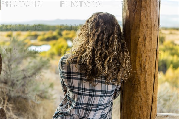 Caucasian woman leaning on wooden porch post