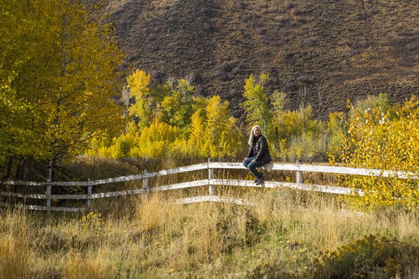 Caucasian woman sitting on wooden fence