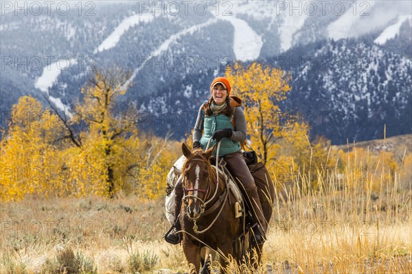 Laughing Caucasian woman riding horse in winter