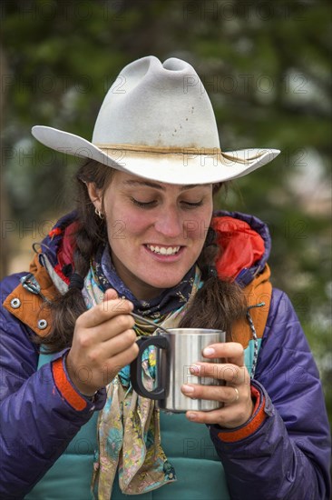 Caucasian woman using spoon with metal cup in winter