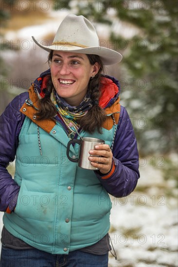 Smiling Caucasian woman holding metal cup in winter