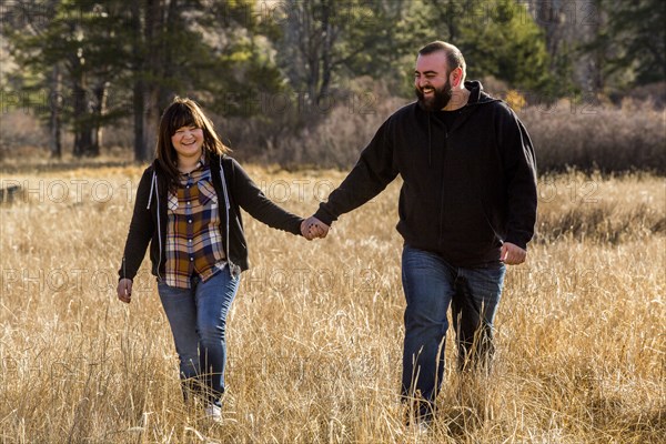 Caucasian couple holding hands in field