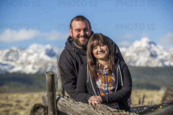 Smiling Caucasian couple leaning on wooden fence