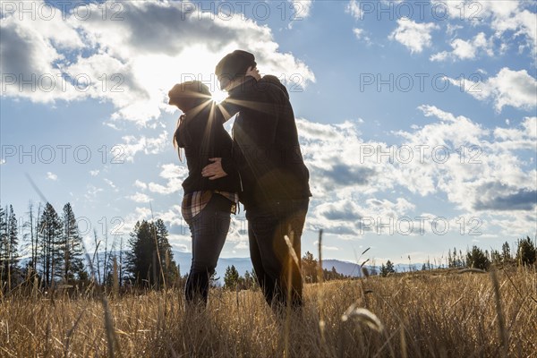 Caucasian couple kissing in sunny field