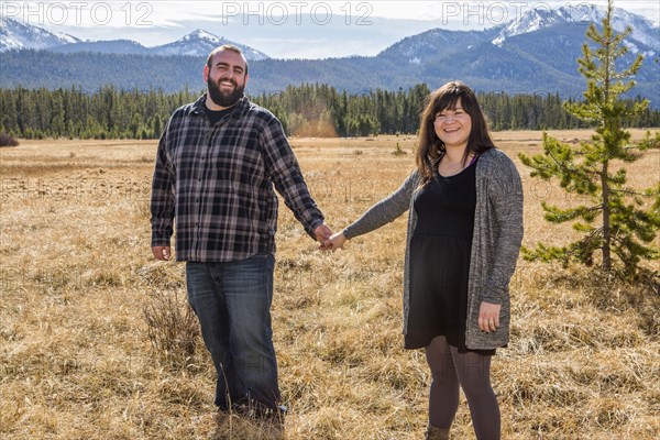 Smiling Caucasian couple holding hands in field
