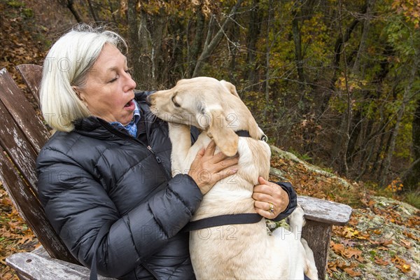 Caucasian woman holding dog in lap outdoors