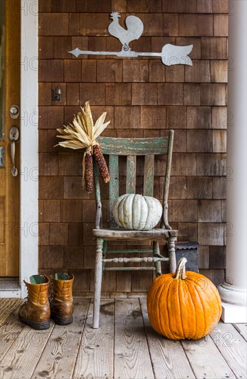 Pumpkins and corn on porch with boots in autumn