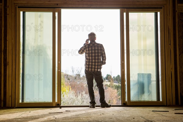 Caucasian man talking on cell phone in doorway