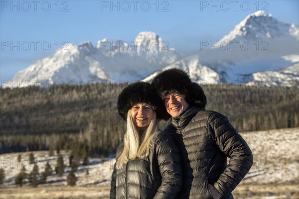 Caucasian couple smiling near mountains in winter