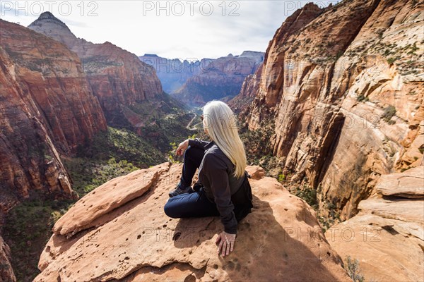 Caucasian woman sitting on rock admiring scenic view of rock formations